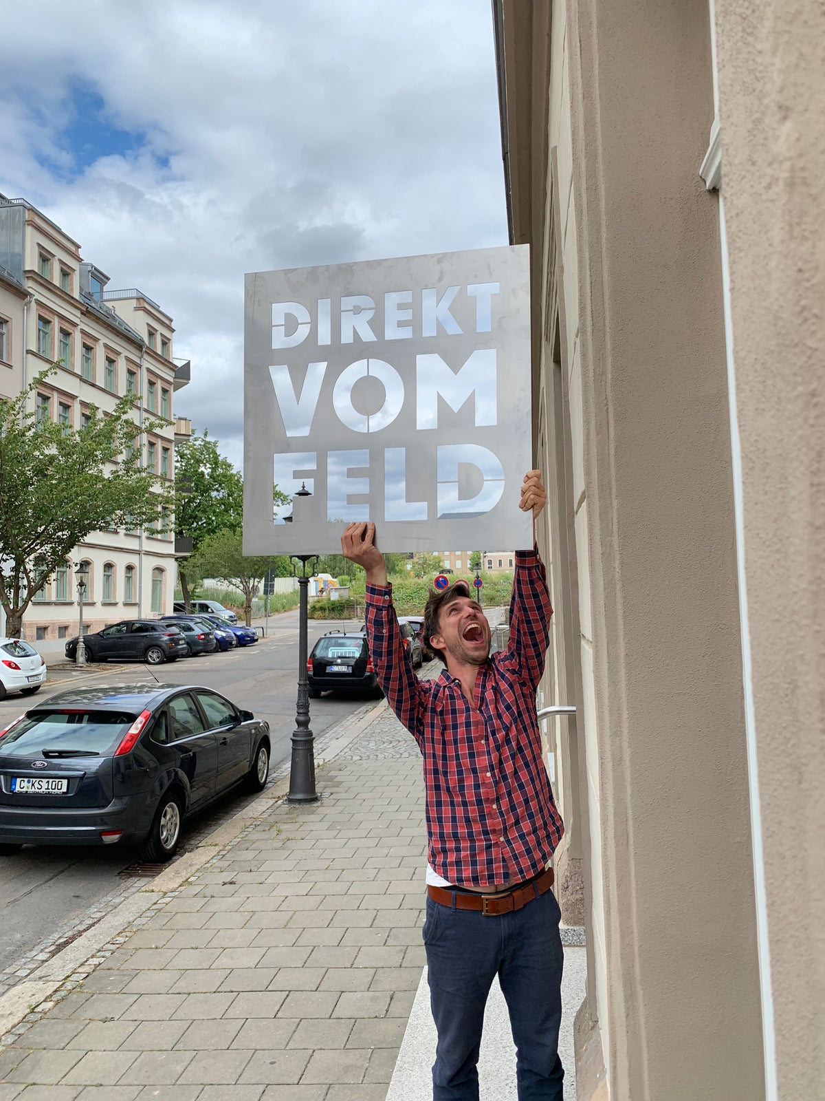Richard bringt 2019 das Schild am ersten Laden auf dem Brühl an